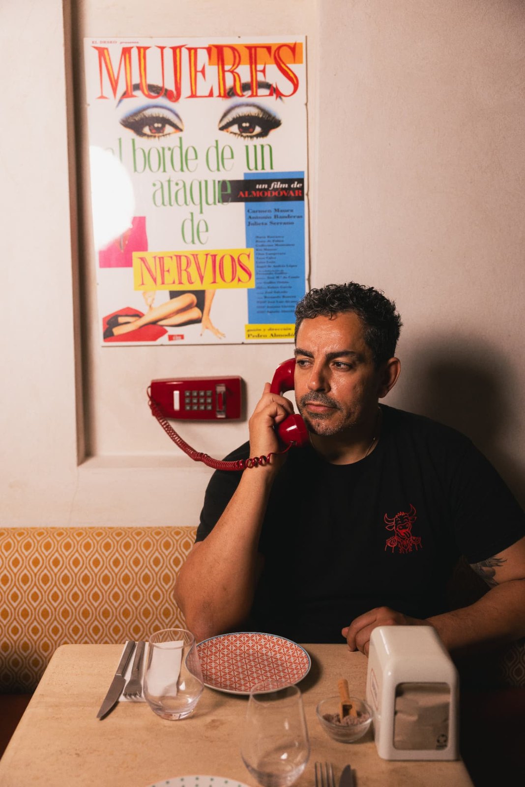 Toufik Seddik au téléphone rouge sous une affiche d'Almodóvar